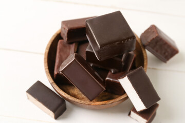 Bowl of tasty bird's milk candies on light wooden background, closeup