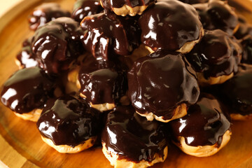 Wooden dessert stand with delicious eclairs, closeup