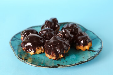 Plate with tasty eclairs on color background