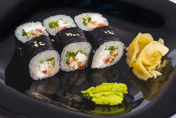 Two triangle pieces of sushi roll with nori seaweed on top. Unagi eel, cucumber, egg omelette, cream cheese inside roll. Asian roll dish isolated on white background. Copy space image with reflection