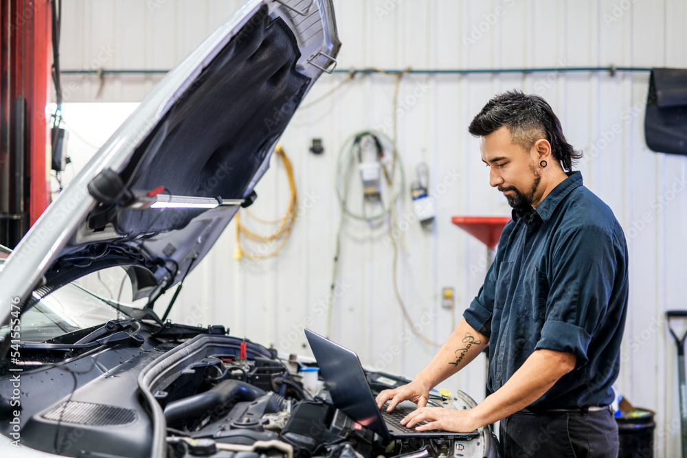 Wall mural Handsome mechanic job in uniform working on car