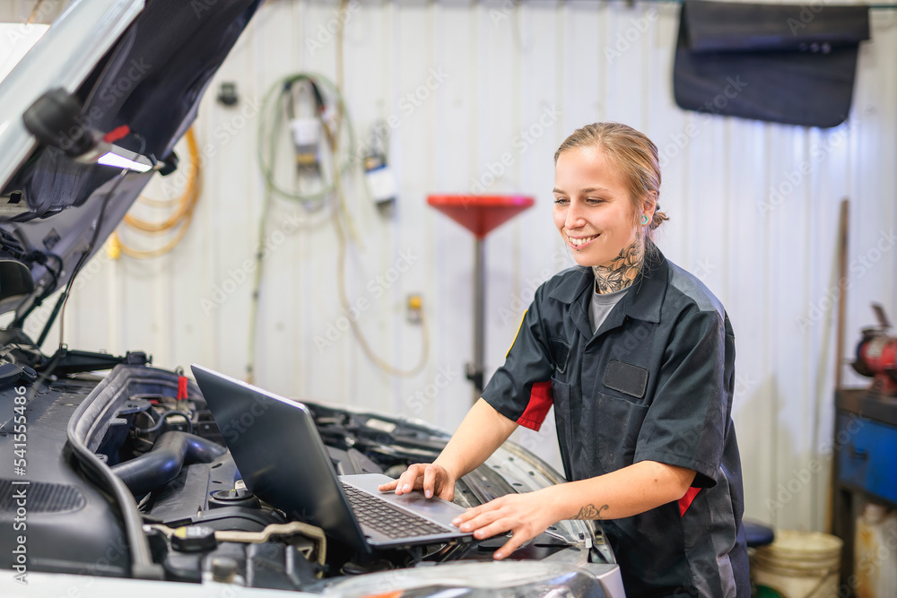 Wall mural Handsome mechanic job woman in uniform working on car