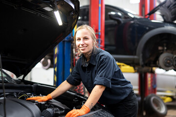 Obraz na płótnie Canvas Handsome mechanic job woman in uniform working on car