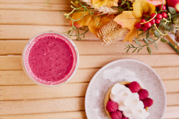 Healthy pink raspberry smoothie with french tart with autumn decorations. Aesthetic breakfast.