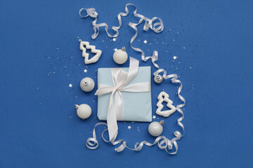 Composition with Christmas gift, decorations and serpentine on blue background