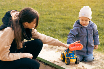 Mother and son playing in sandbox. Little builder. Education, and imagination, purposefulness concept. Support childhood parenthood symbol - 541558066