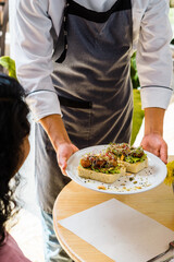 Unrecognizable person placing a plate on the customers' table.
