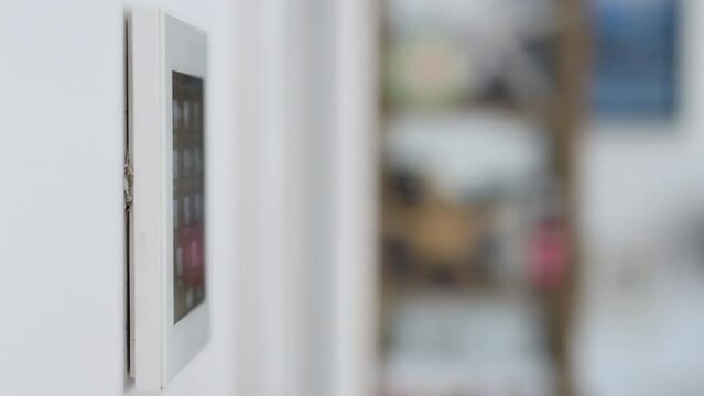 Close-up of man's hand adjusting the temperature on a home automation screen.