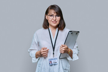 Portrait of woman with clipboard and name card, on grey background