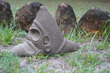 Taino Antique Stone Cemi Idol Figure sitting on the ground on top of grass. Taino Indian Mythology.