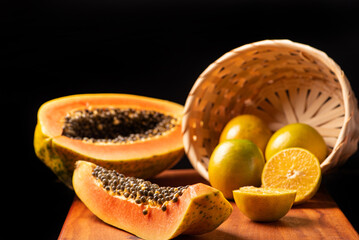 Papaya and oranges, scene with sliced ​​papaya and oranges over rustic wood, selective focus.