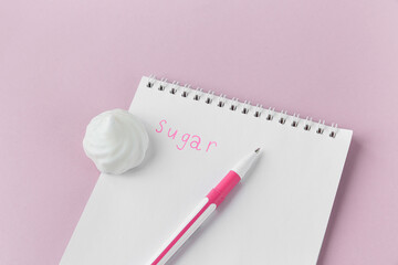 Notepad and pen on a pink background, the inscription sugar