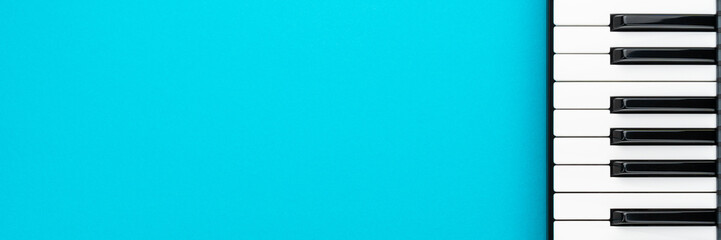 Top view of piano keys with copy space. Minimalist photo of midi keyboard over turquoise blue background.