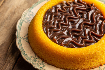 Homemade pool-style carrot cake with milk chocolate brigadeiro filling, on top of the old plate with top view on a rustic wooden table and selective focus
