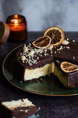 Ukrainian cheesecake syrnyk with chocolate and almond glaze on green plate on dark background .