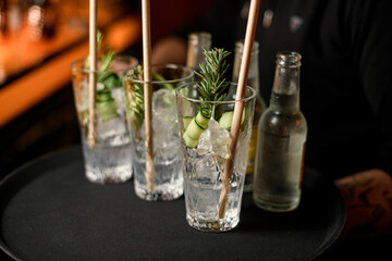 close-up on glasses with gin tonic cocktail and bottles on tray