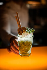 close-up of glass with iced mojito cocktail with drinking straw in male hand