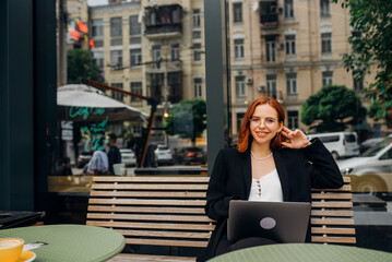 Fototapeta premium Beautiful woman working on laptop at outdoors cafe
