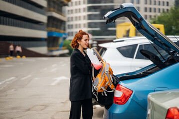 A woman puts things in the car