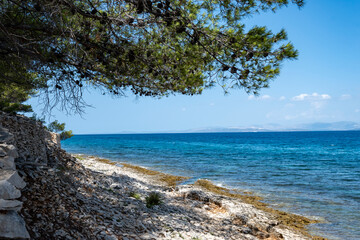 Fototapeta na wymiar Beautiful blue, turquoise sea and stone dry wall built on the edge of the coast at Brac island, Croatia