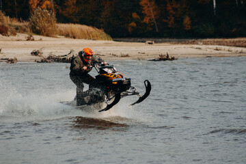 sportsman on a snowmobile rides on the water