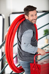 male builder carrying red pipe on his shoulder