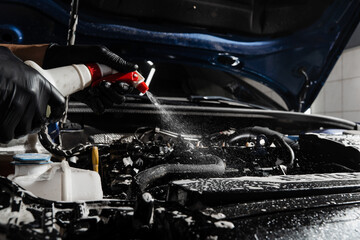 Washing car engine with spray and detergent in detailing auto service. Detailing cleaning motor...