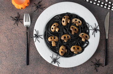 Black Italian spaghetti and mushrooms in form of skulls, idea of cooking vegetarian food for...