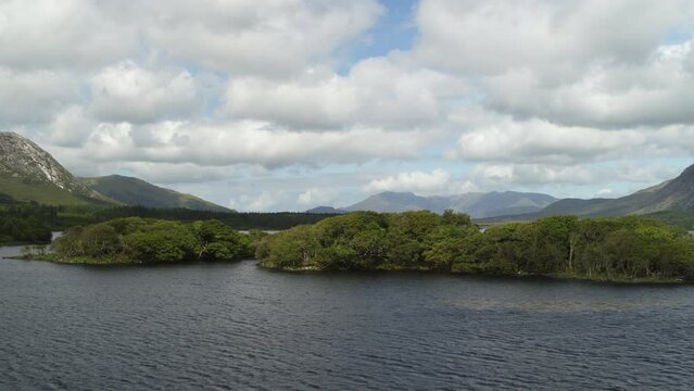 Aerial flyover view passing lake and trees at Lough Inagh / Galway, Ireland