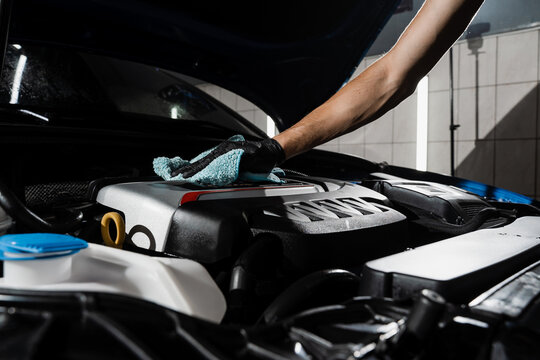 Wiping the car engine with microfiber after washing motor in car detailing service. Detailing cleaning motor from dust and dirt.