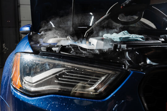 Steaming washing of motor of auto in detailing auto service. Process of steam cleaning car engine from dust and dirt.