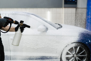 Process of spraying foam on the car body in the garage. Second phase of detailing washing in car...