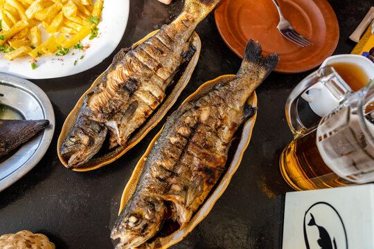 Whole grilled trout fish with head on the table