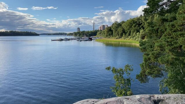 Seascape one summer day. Calm dark water and nature. Small Harbour with boats in the distance. H&auml;sselby, M&auml;laren, Stockholm, Sweden, Scandinavia, Europe.