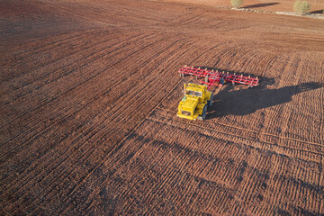 Pre-sowing spring soil preparation. A tractor with a harrow is working in the field. Shooting from...