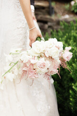 Close up of woman in wedding dress holding beautiful flower bouquet while standing in park