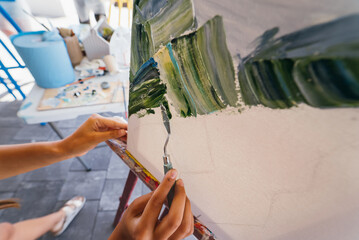 Close-up of woman's hand applying paint to a canvas