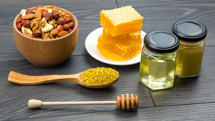 Fresh flower honey of different varieties, pollen and honeycomb with spoons on a wooden background....
