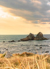 Picturesque sunset on the autumn lawn of Itoshima coast and its natural landmark popular for its Sakurai Futamigaura's Meoto Iwa Couple Rocks adorned by a Shintoist straw made rope off Fukuoka.