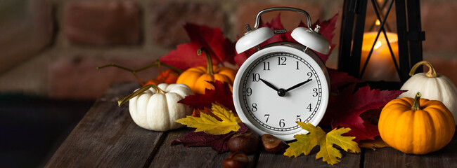 Fall winter time change concept. Autumn composition with retro alarm clock, bright yellow and red...