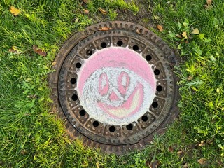 Bemalter Gullideckel mit einem Smiley