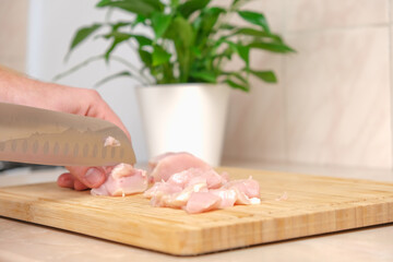 Obraz na płótnie Canvas Defrosted raw chicken fillet on cutting board. Slicing fresh raw chicken breast with sharp knife for cooking chopped chicken cutlets on a bamboo wooden cutting board for slicing. Kitchen knife test.