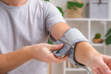 A man measures blood pressure with a white electric tonometer lying on a white table. Measurement of pressure and pulse. The concept of a healthy lifestyle.