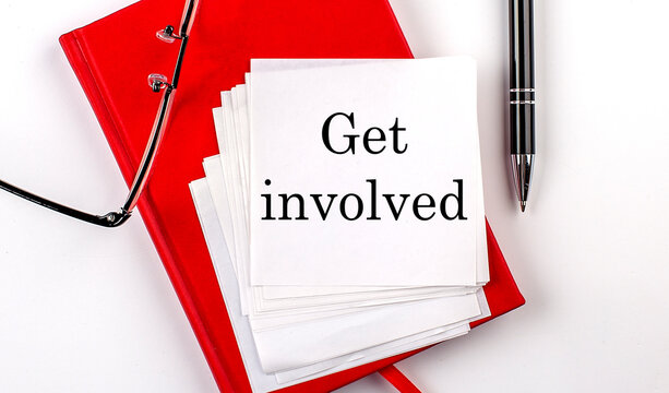GET INVOLVED text on sticker on red notebook with pen and glasses