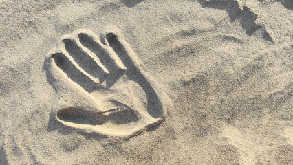 Fototapeta na wymiar Handprint in sand, copy space. Top view, close-up