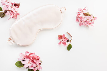 Sleeping mask and spring flowers on white backgrount, copy space