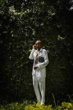 a black woman dressed fashionable posing for a portrait in a garden