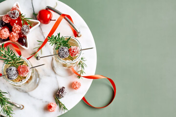 Christmas cocktail with sparkling wine, rosemary and cherry. Winter xmas and new year holidays champagne drink, top view.