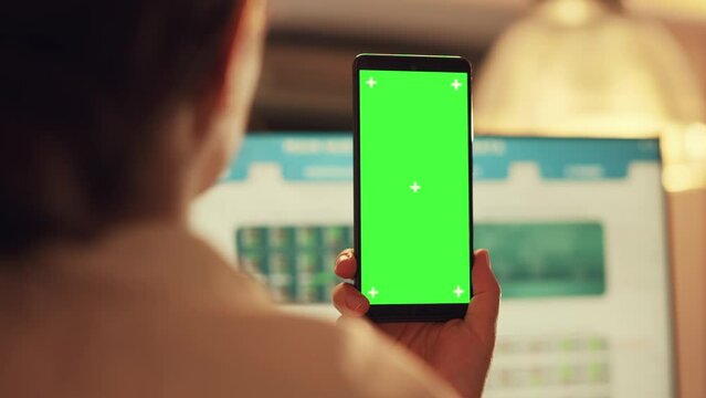 Female manager using smartphone with greenscreen display, analyzing isolated chroma key template and stock market real time statistics. Working on blank copyspace mockup at sunset.