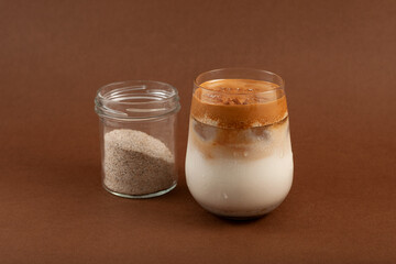 Dalgona Misu or Dalgona Misugaru Latte on brown background.  Korean refreshing drink made from roasted multi grain powder, milk and coffee. Popular breakfast drink. Selective focus
